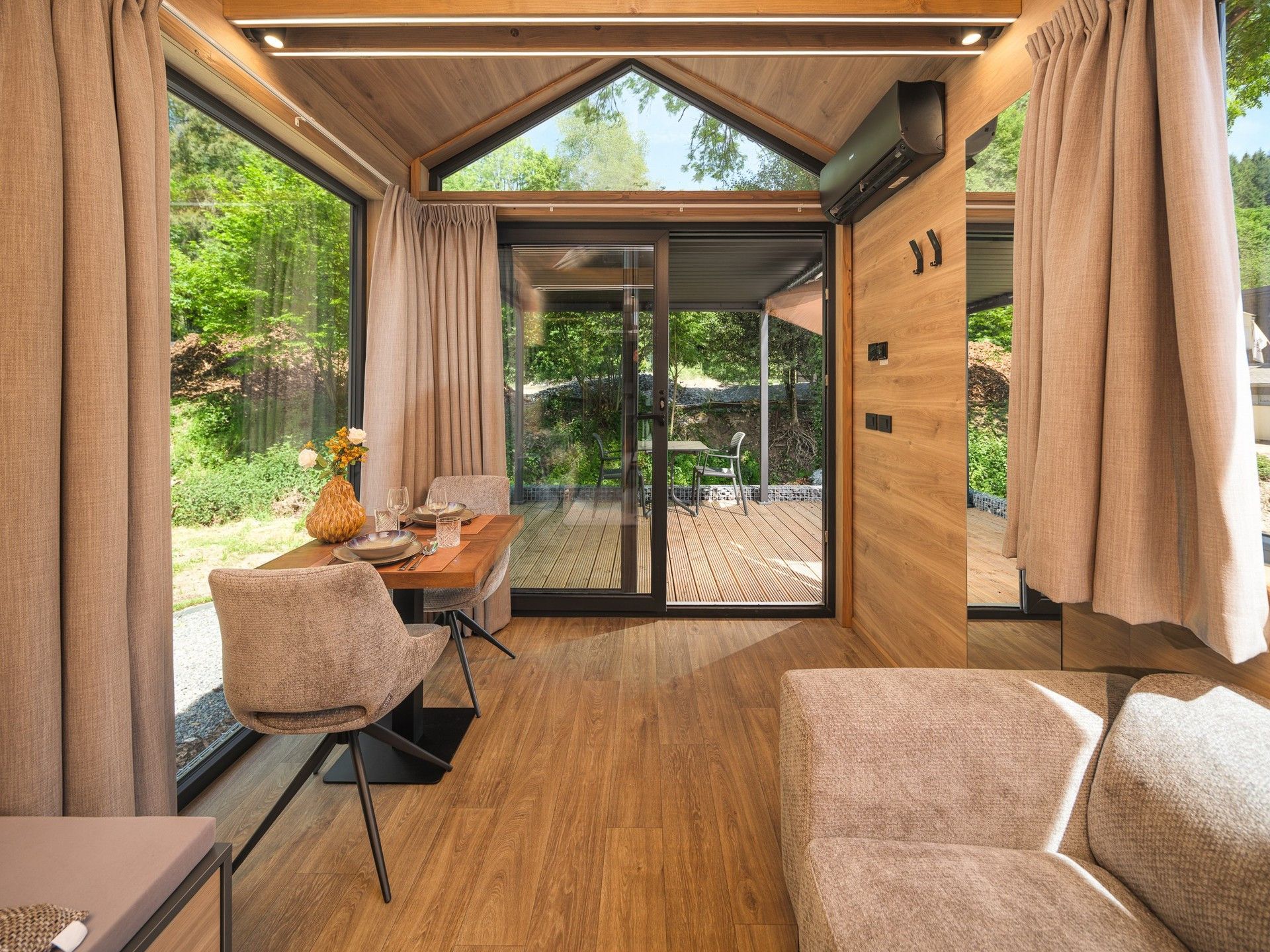 Een modern interieur met een eethoek, zitplaatsen en uitzicht op het buiten.