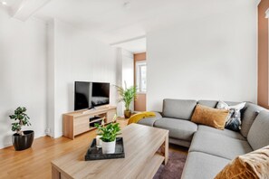 A modern living room with a flat-screen TV, a grey sofa, a wooden coffee table, and a potted plant. - Modern Studio – Prime Central Location (Tromsø)