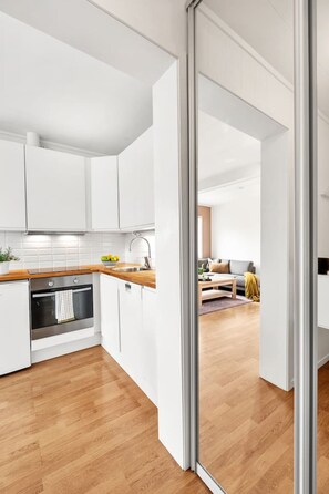 A modern kitchen with white cabinets, a wooden countertop, and a stainless steel oven. - Modern Studio – Prime Central Location (Tromsø)