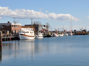 A marina with multiple boats docked, a clear sky, and buildings in the background. - Holiday Apartment With 2 Bedrooms (Heiligenhafen)