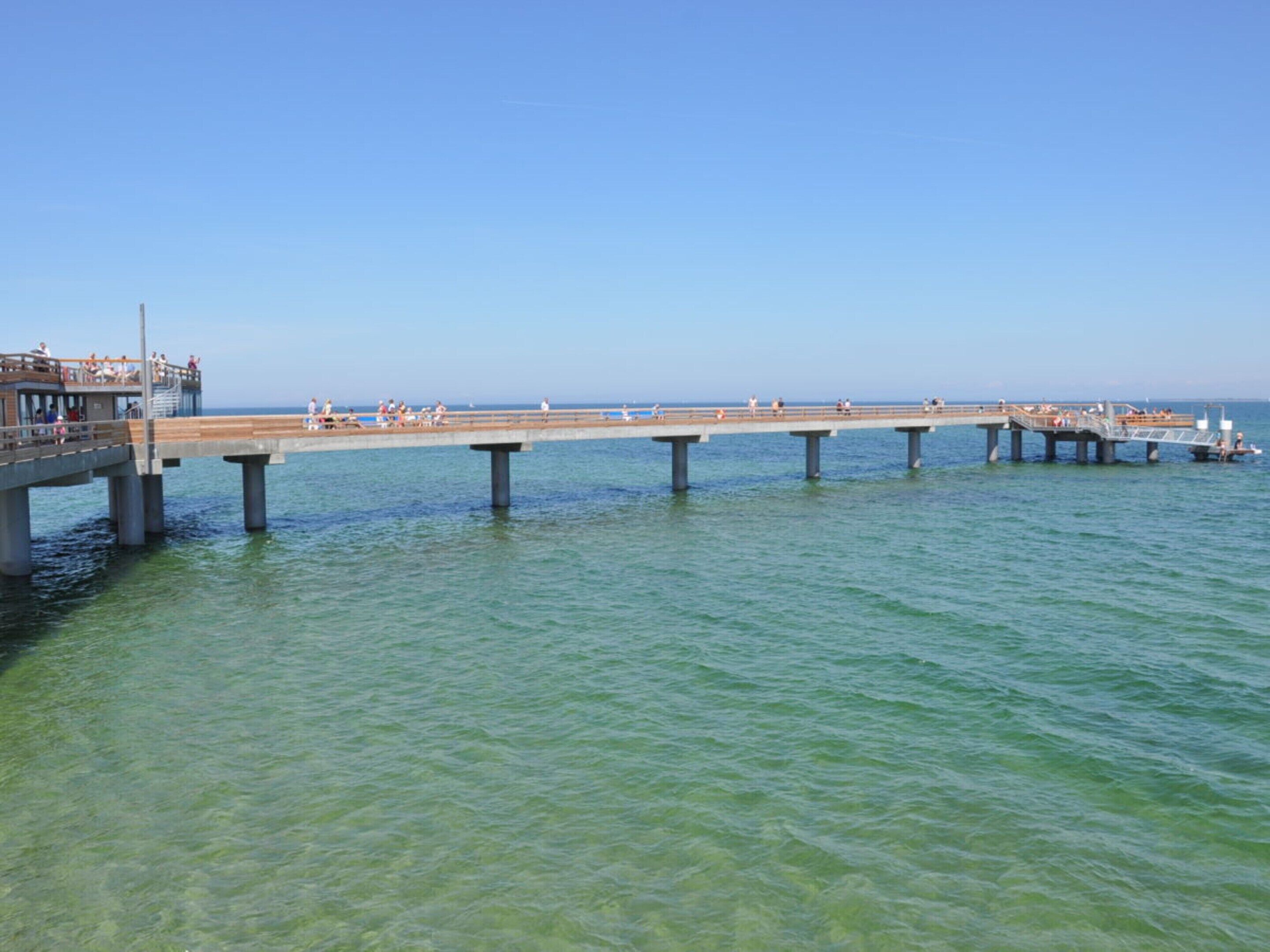 Eine Pier, die sich ins Wasser erstreckt, mit Menschen, die darauf entlanggehen.