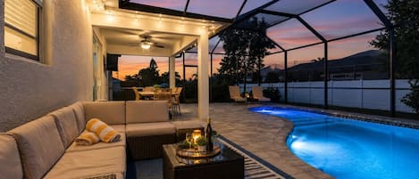 An outdoor patio area with a pool, seating, and a pergola structure.