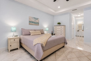 A bedroom with a bed, bedside tables, a dresser, and a painting on the wall. - Cape Coral home with Pool, Spa & Game Room (Cape Coral)