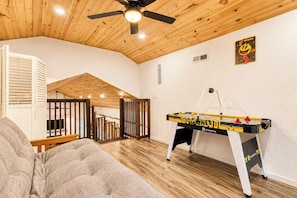 Une pièce avec une table de baby-foot, un ventilateur de plafond et un plafond en bois.