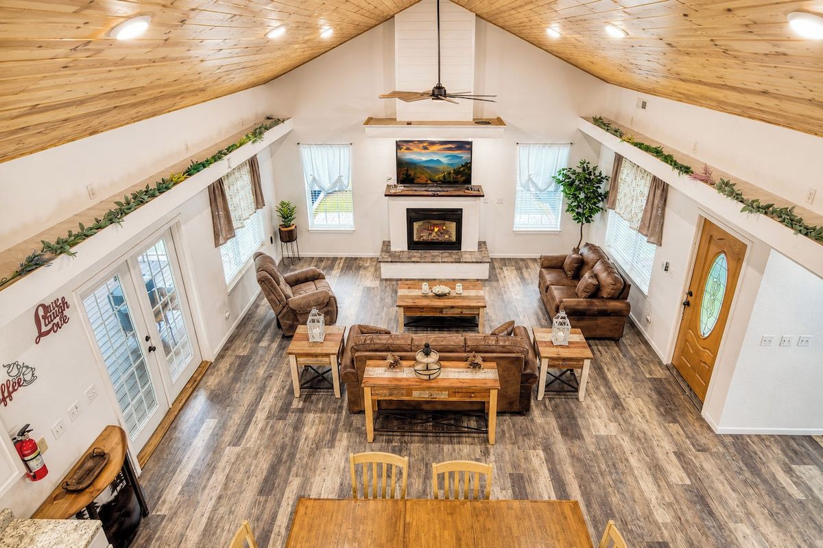 Un vaste espace de vie aménagé dans un style industriel, avec une cheminée, des meubles en bois et un plafond haut.