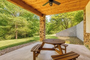 A wooden pavilion with a ceiling fan, surrounded by a stone wall and a grassy area with trees. - 5 King Bedroom Mtn Lodge Hot Tub, Yard, & Games (Sevierville)