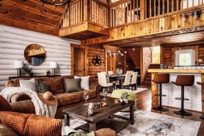 A log cabin interior with a dining area, kitchen, and a loft bedroom. - Family Retreat! Private Pool, Hot Tub, Game Room! (Sevierville)