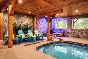 An indoor swimming pool area with wooden beams, stone walls, and Adirondack chairs. - Family Retreat! Private Pool, Hot Tub, Game Room! (Sevierville)