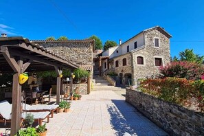 A stone building with a covered patio area, outdoor seating, and a stone wall with plants. - TWO Dog-Friendly Gites in the Cévennes with 2 Private Pools and enclosed gardens (Gagnières)