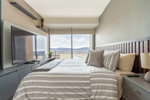 A modern bedroom with a large bed, a TV, and a view of the outdoors. - Casa Cardonal  Cosmos Homes (Zibatá)
