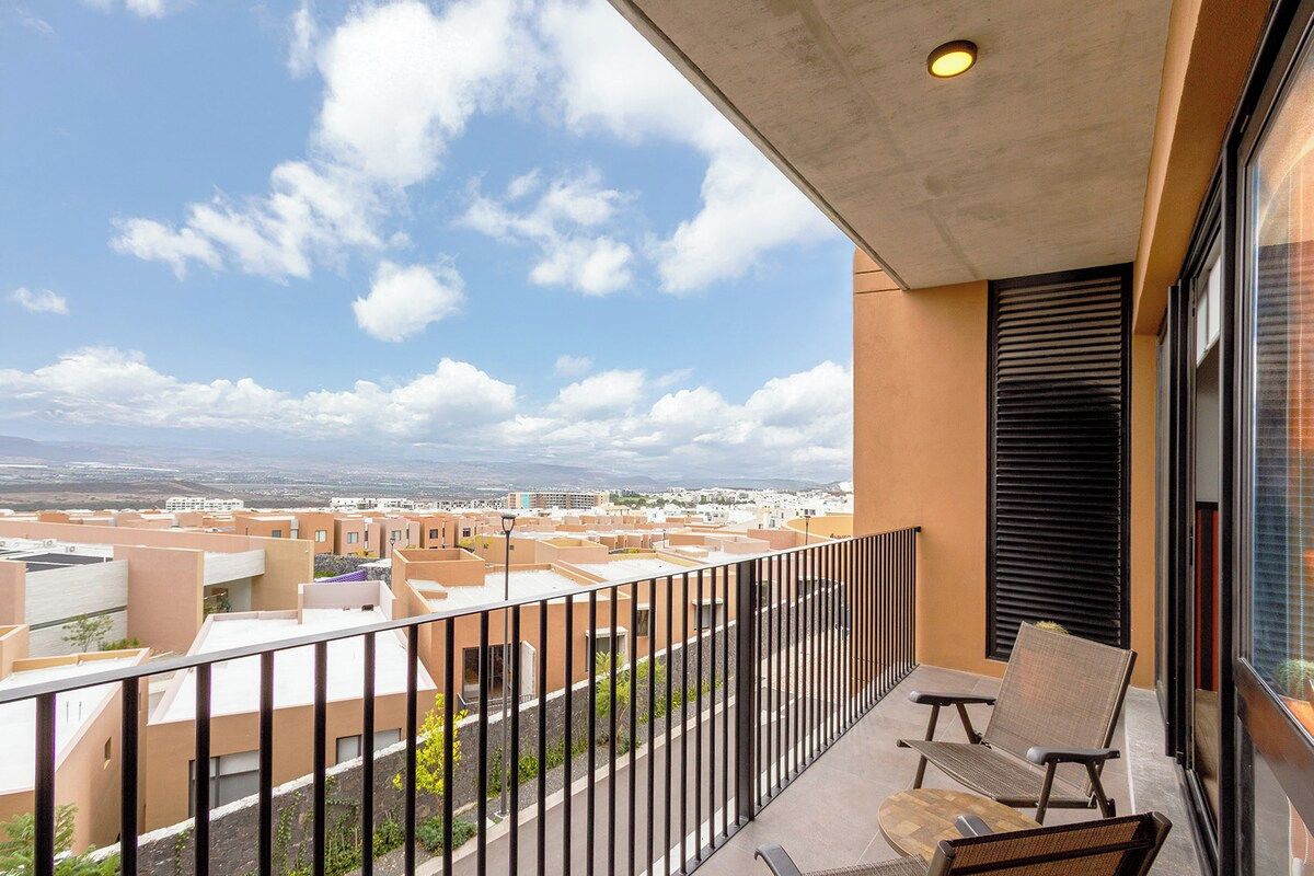 Varanda com vista para a paisagem urbana, uma cadeira e uma mesa.