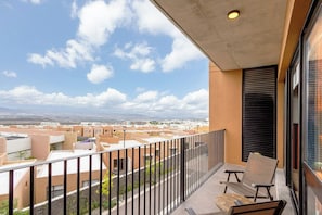 Ein Balkon mit Blick auf eine Stadtansicht, einem Stuhl und einem Tisch.
