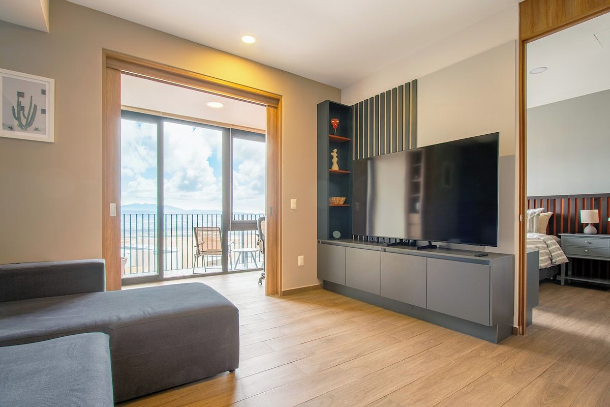 Ein modernes Wohnzimmer mit einer Couch, einem Flachbildfernseher und einem Balkon mit Blick.