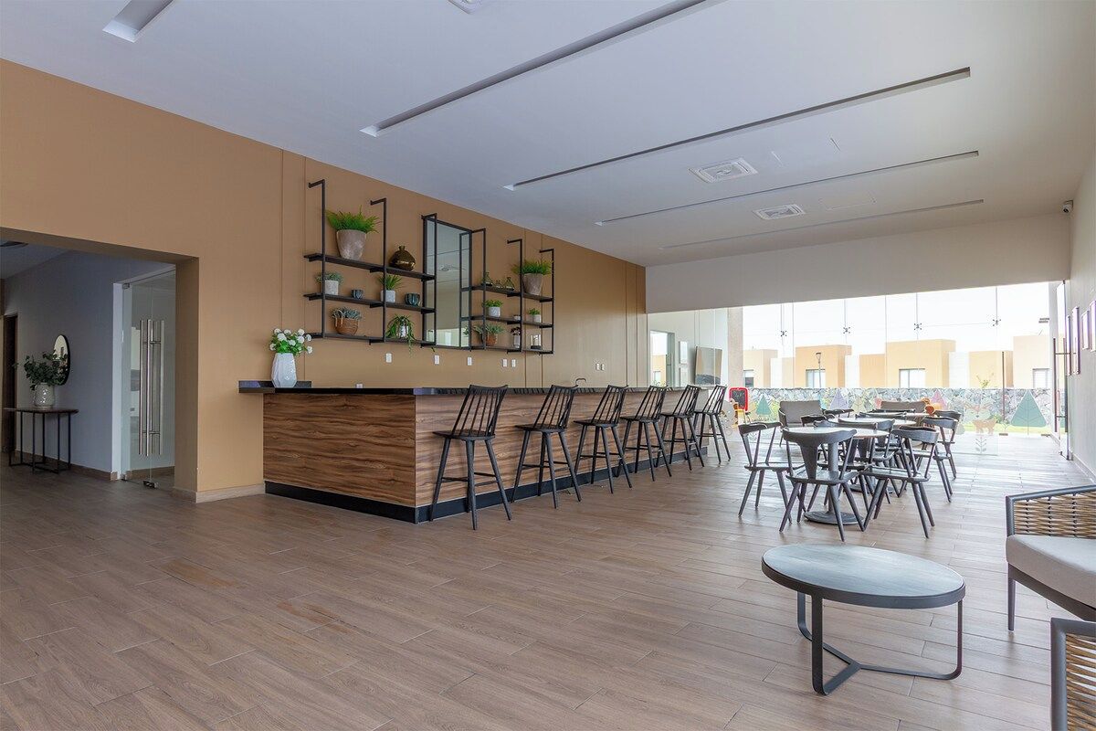 A modern interior with a reception desk, chairs, and a dining area.