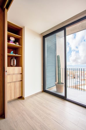 Ein Zimmer mit einem Holzkasten, einer Schiebetür zum Balkon und einem Kaktus im Topf.
