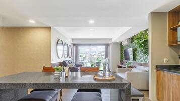 Una cocina moderna con una isla central, zona de estar con sofás y vistas a la ciudad.