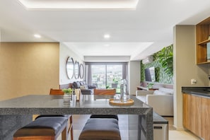 Una cocina moderna con una isla central, zona de estar con sofás y vistas a la ciudad.