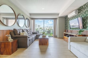 Una sala moderna con un sofá modular, una mesa de centro y un televisor sobre una pared con diseño.
