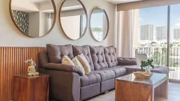 A modern living room with a large sofa, two side tables, and three wall-mounted mirrors.