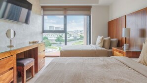 Quarto de hotel moderno com uma cama grande, uma escrivaninha com espelho, televisão e vista para a cidade.