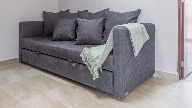 A modern living room with a grey sofa, a throw blanket, a pendant light, and a tiled floor. - Casa Berilo  Cosmos Homes (Zakia)