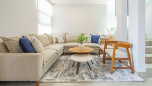 A modern living room with a sectional sofa, two coffee tables, and a wooden chair. - Casa Berilo  Cosmos Homes (Zakia)