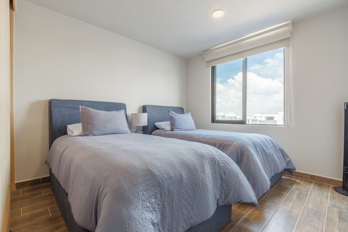 Une chambre d’hôtel avec deux lits, une grande fenêtre et un téléviseur à écran plat.