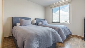 A hotel room with two beds, a large window, and a flat-screen TV. - Casa Berilo  Cosmos Homes (Zakia)