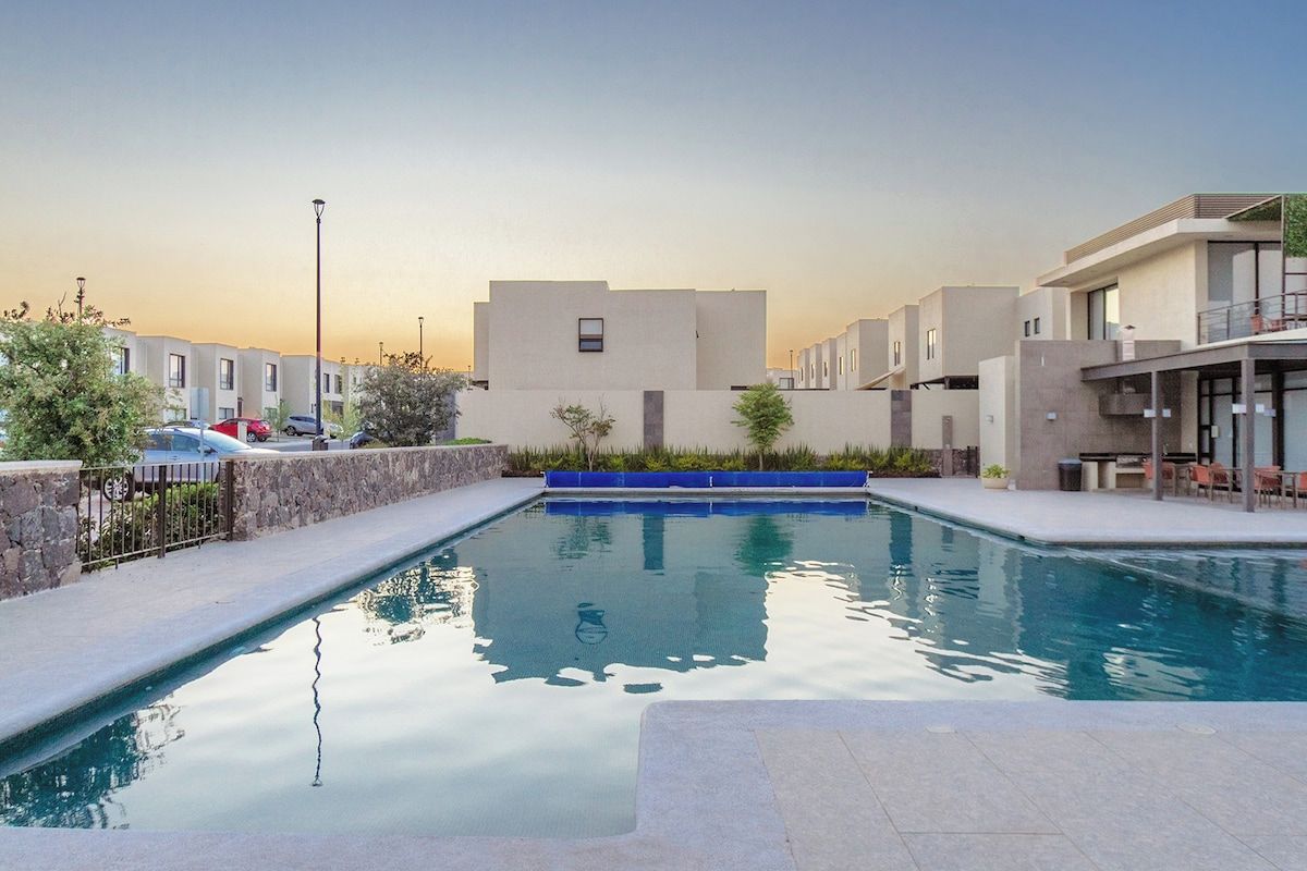 Une piscine offrant une vue dégagée sur les bâtiments environnants et bordée d’un mur en pierre.