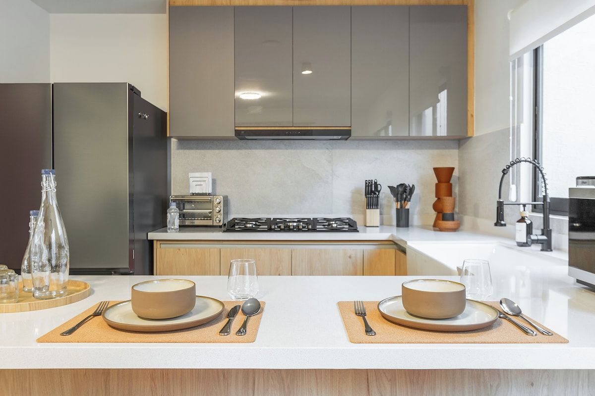 A modern kitchen with a central island, stainless steel appliances, and a large window providing natural light.