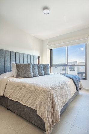 Ein modernes Schlafzimmer mit einem großen Bett, einer Kopfteil und einem großen Fenster.