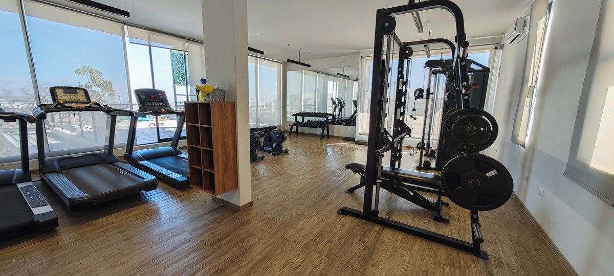 Una palestra con tapis roulant, una panca per pesi e una rack per squat.