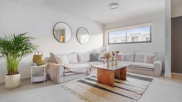 A modern living room with a sofa, a coffee table, and a large potted plant.