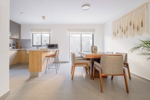 Eine moderne Küche mit Kochinsel, Barhocker und einem Essbereich mit Holztisch und Stühlen.