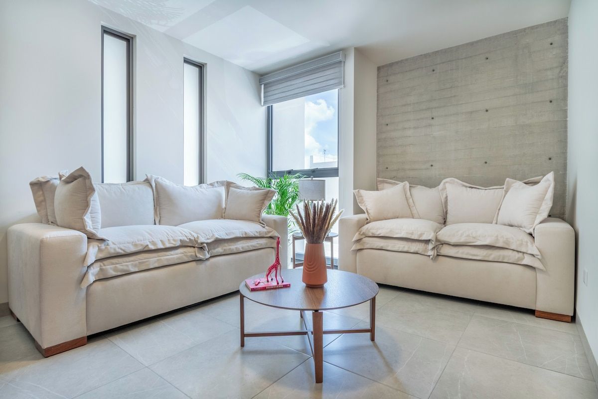 Un salon moderne avec deux canapés, une table basse et une grande fenêtre.