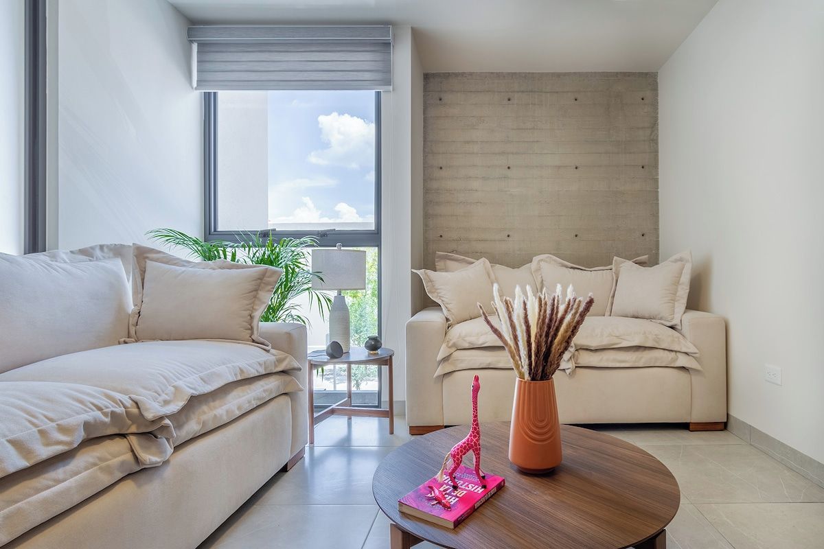 A modern living room with two sofas, a coffee table, and a bookshelf.
