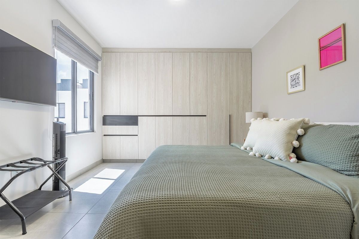 A modern bedroom with a bed, a TV, and a window.