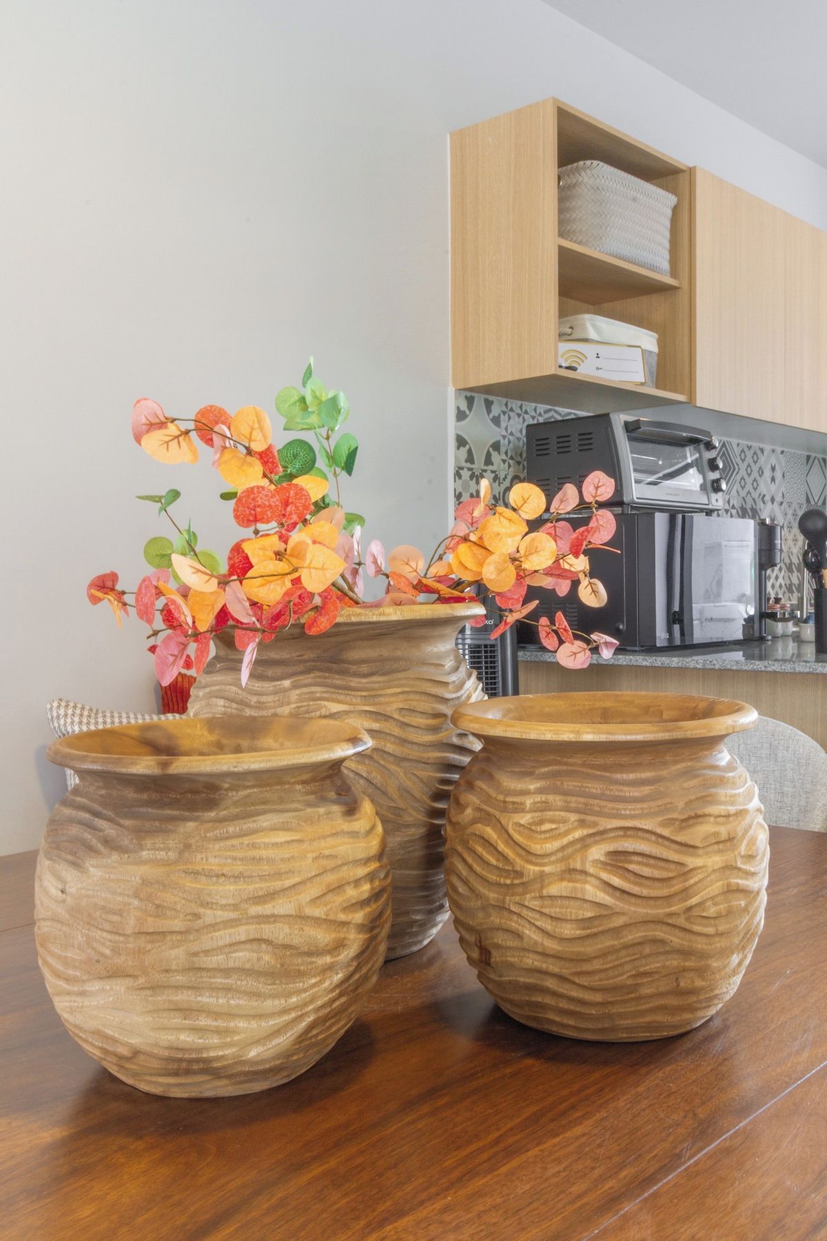 Three wooden vases with a wavy texture on a wooden table.