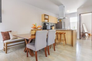 Eine moderne Küche mit Essbereich, ausgestattet mit einem Holztisch, Barhocker und einem eingebauten Ofen.