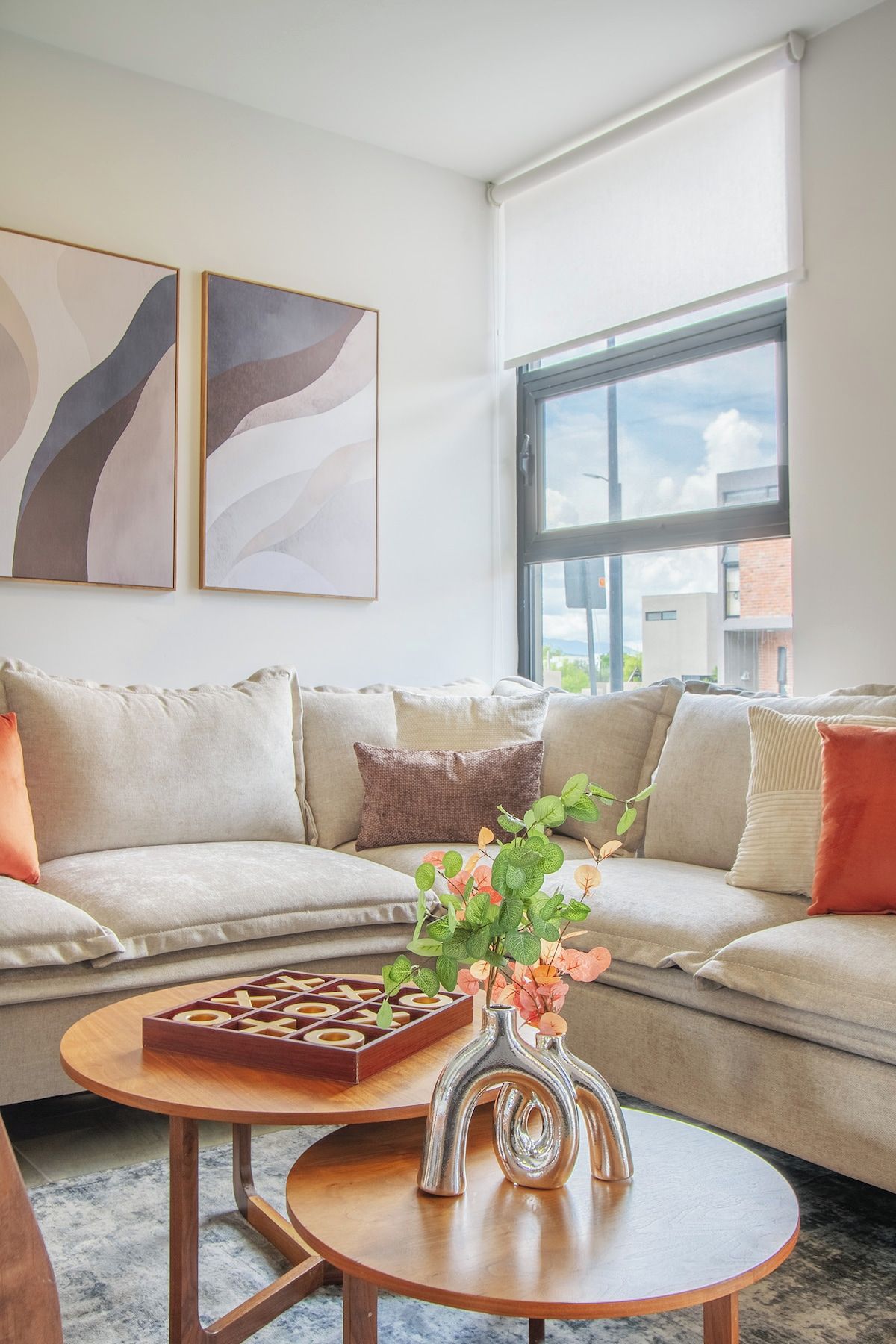 A modern living room with a sofa, a coffee table, and two abstract paintings on the wall.