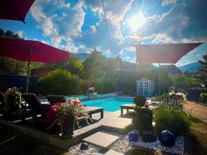 Ein Garten mit Swimmingpool, Liegestühlen und Sonnenschirmen.