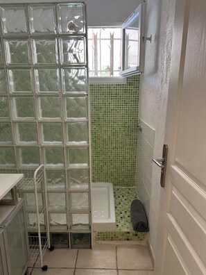 Ein Badezimmer mit Duschkabine aus Glas, einer weißen Badewanne und einer grünen Fliesenwand.