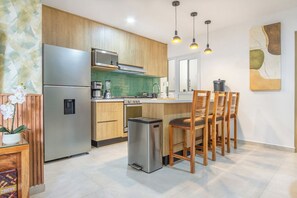 Een moderne keuken met houten kastjes, roestvrijstalen apparatuur en een bar voorzien van houten krukken.