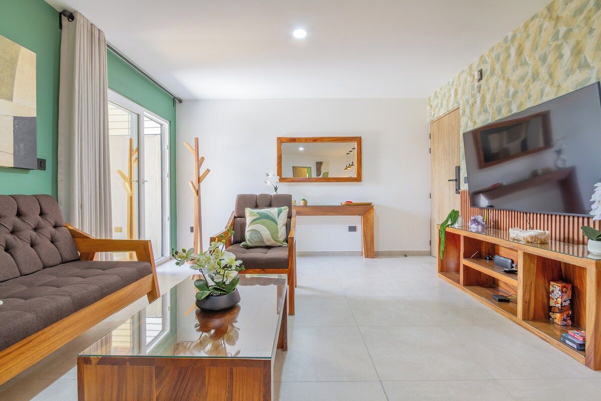 Una sala de estar moderna con sofá, sillón, mesa de centro y mueble para televisión.