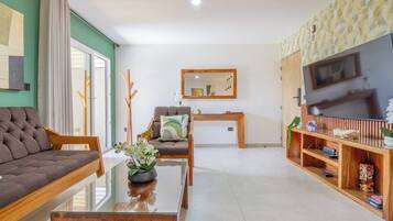 Una sala de estar moderna con sofá, sillón, mesa de centro y mueble para televisión.