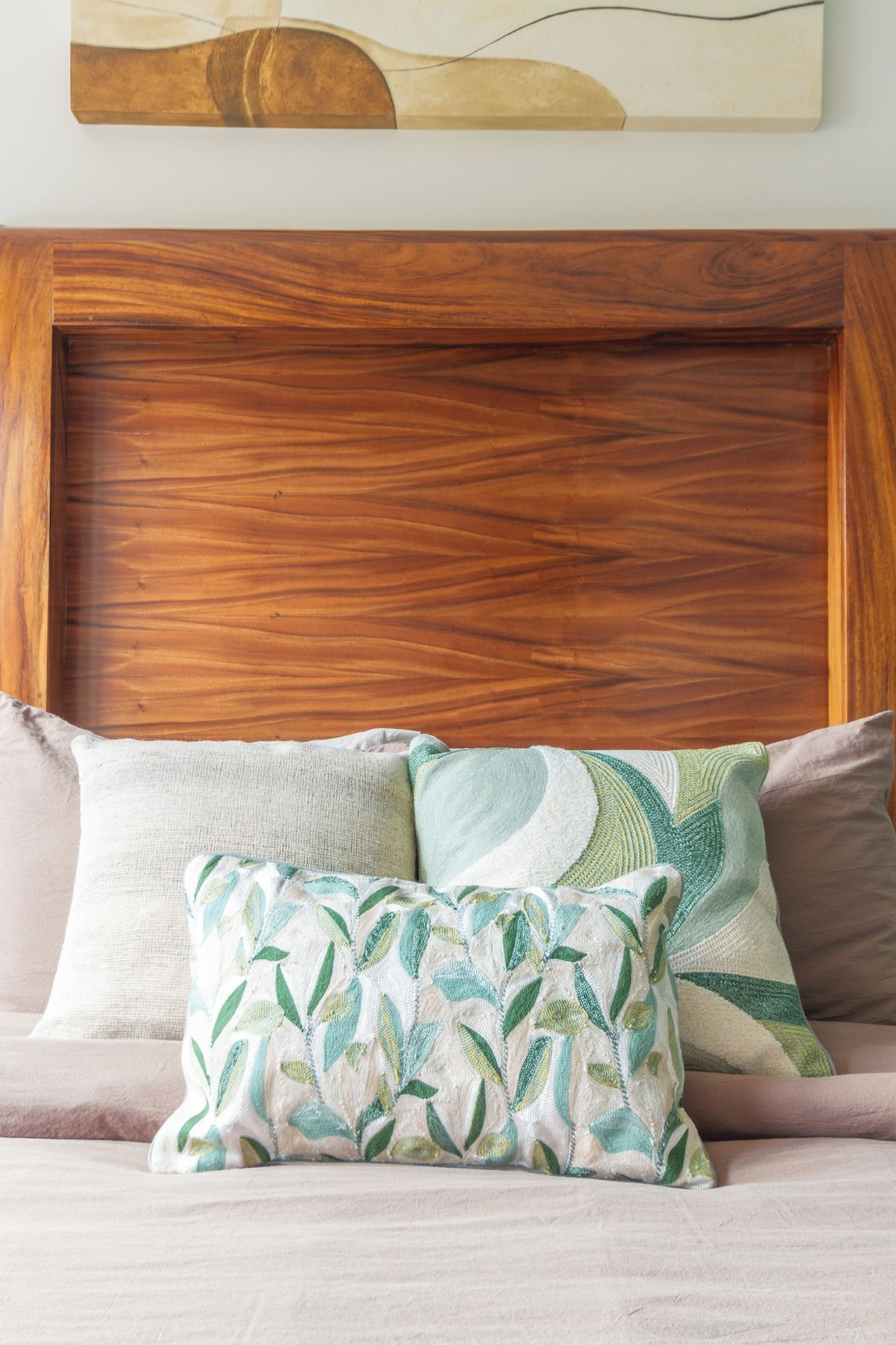 A bed with a wooden headboard, a patterned pillow, and a plain pillow.