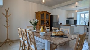 A modern kitchen with a dining area, wooden chairs, a table, and a coat rack. - Vrbo Property (Saint-Jeures)