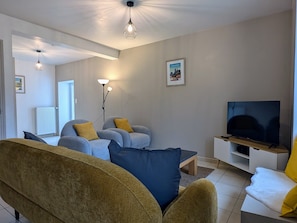 Ett vardagsrum med en soffa, fåtöljer, en tv och en lampa.