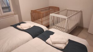 Un dormitorio con dos camas, una cuna de madera y una cuna blanca.