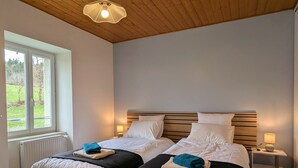 A room with two beds, a wooden ceiling, a window, and a radiator. - Vrbo Property (Saint-Jeures)